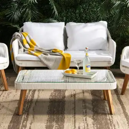 Conjunto de muebles de exterior Safavieh dispuestos con una manta y una bandeja con cócteles.