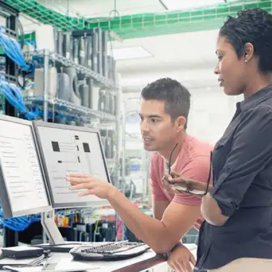 Dos personas trabajan juntas frente a una computadora y analizan los detalles de fabricación de 4XEM.
